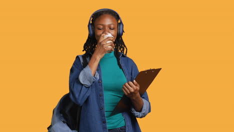 Teenager-drinking-caffeinated-beverage,-examining-clipboard,-studio-background