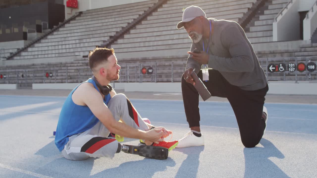 다채로운 남성 코치와 장애인 운동 선수가 훈련 기간 동안 연설하고 있습니다.