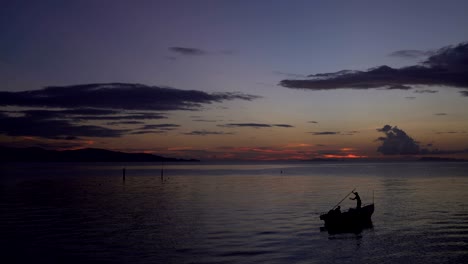 silhouetted boat in the sea at sunset