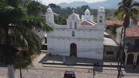 Low-aerial-through-town-plaza-to-Iglesia-San-Jose-Obrero-church,-Copan