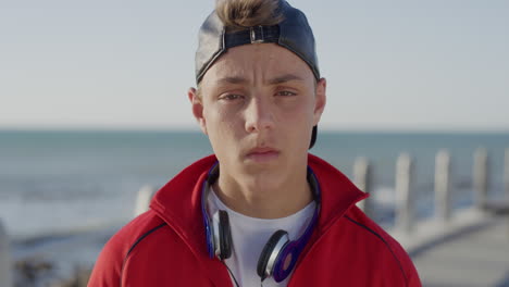 portrait young caucasian teenager boy looking serious at camera on calm sunny seaside