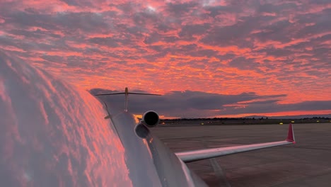 extraordinario cielo rojo reflejado en la parte superior del fuselaje de un jet justo antes de la puesta del sol, vista desenfocada, con un auto sígueme en la parte trasera