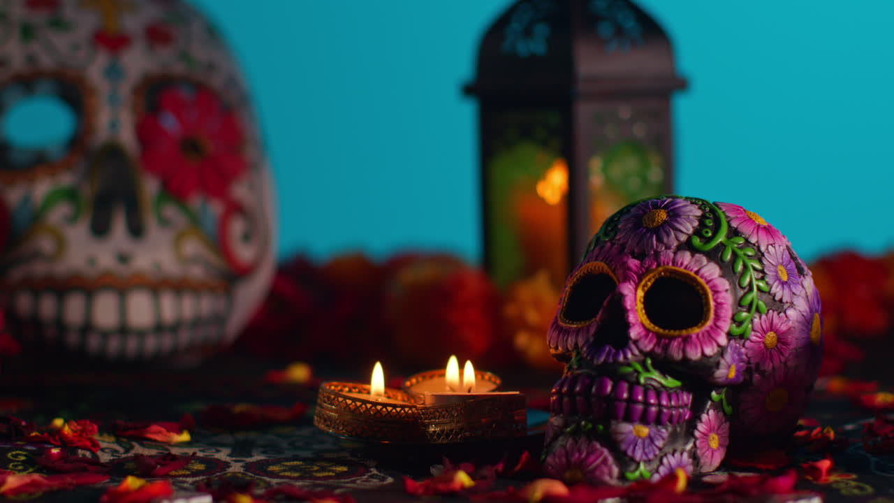 primer plano de cráneos y máscaras decoradas rodeadas de velas y pétalos de flores celebrando la fiesta mexicana de dia de muertos o día de los muertos contra un fondo azul 1