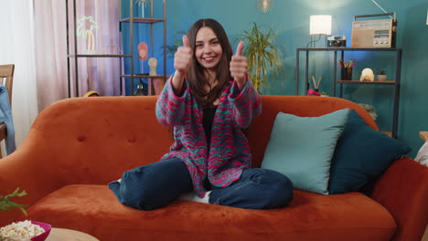 happy caucasian woman looking approvingly at camera showing thumbs up like positive sign good news