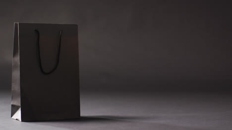 Black-gift-bag-with-black-handles-on-dark-grey-background-with-copy-space