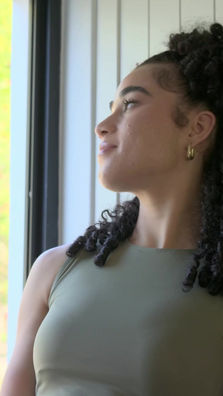 Vertical video: Holding smartphone woman in olive top reading texts and sipping ribbed mug at home