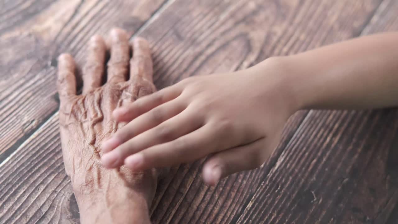 la mano de un niño tocando la mano de una persona mayor