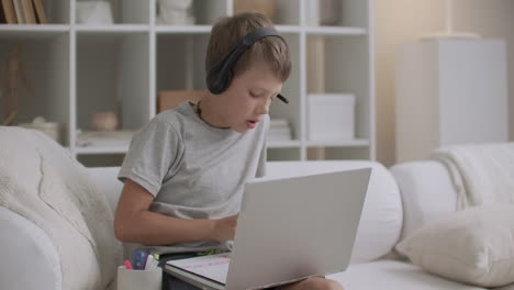 Un-Niño-Con-Auriculares-En-La-Cabeza-Y-Una-Computadora-Portátil-En-La-Mesa-Está-Dibujando-En-Casa-Durante-El-Período-De-Aislamiento-Durante-La-Pandemia-De-Coronavirus