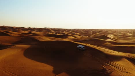 Aerial-view-of-4x4-off-road-land-vehicle-taking-tourists-on-desert-dune-bashing-safari-in-Dubai,-UAE