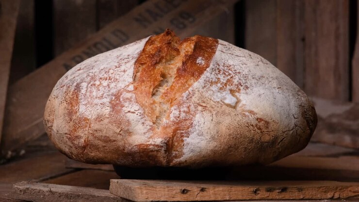 Whole Loaf Of Sourdough Bread Rotating On Wooden Table