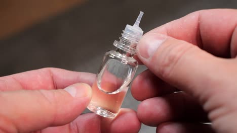 a man holding an e-liquid bottle for an e-cigarette