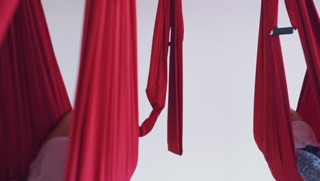 ladies practice modern aerial yoga pose lying in hammocks