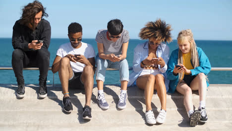 Zeitgenössische-Verschiedene-Freunde-Mit-Smartphones-Am-Meer