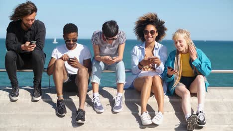 contemporary diverse friends with smartphones on seafront