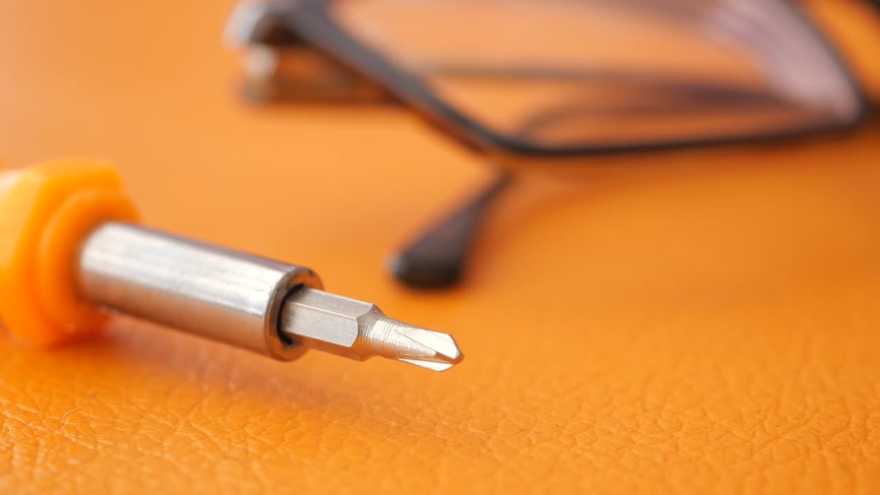 Screwdriver and Glasses on Orange Background