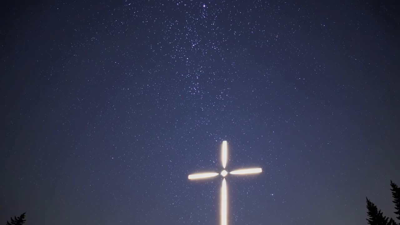A serene night sky with a glowing cross in the foreground, captured from a low angle