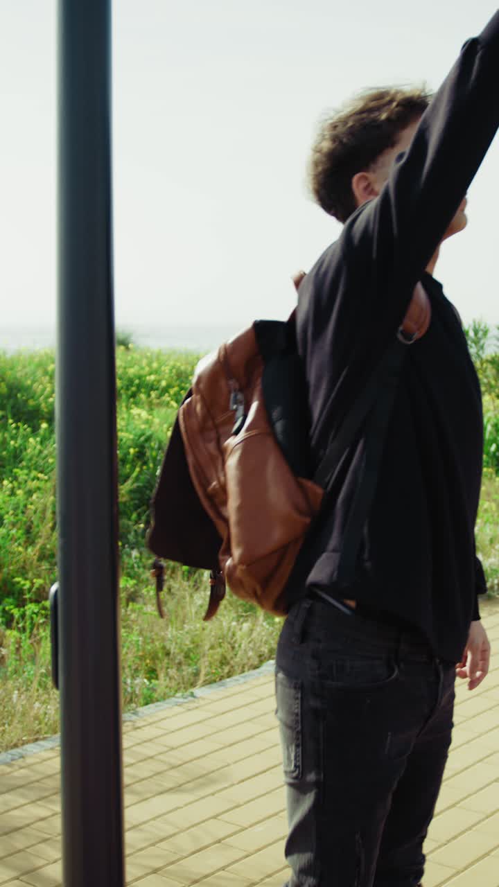 Man With A Backpack On The Sidewalk Waiting For The Bus To Come