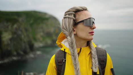 woman with raincoat and braids by the sea
