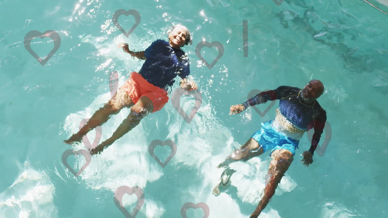 Two people floating in pool with heart shapes overlay animation