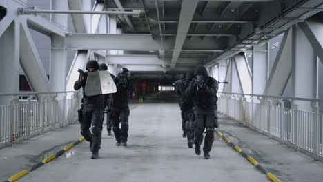 SWAT-team-walking-on-bridge.-Masked-military-soldiers-using-rifles