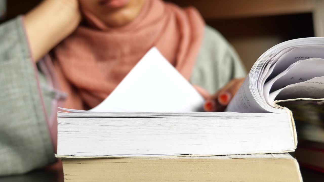 히자브 를 입은 여자 가 책 을 읽고 있다