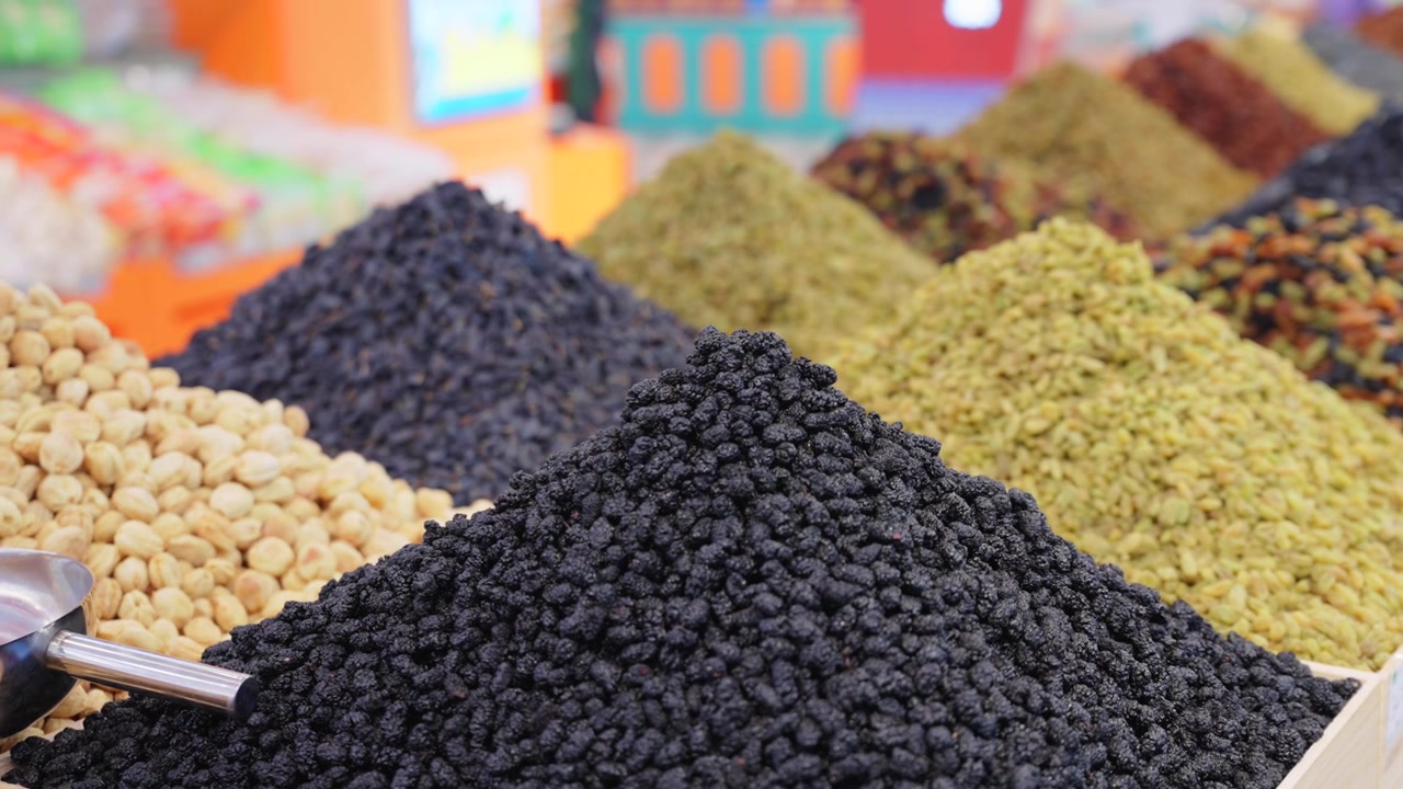 Verschiedene getrocknete Früchte aus Xinjiang, ausgestellt in einem lokalen Spezialitätengeschäft. Mehrfarbige Rosinenhaufen und Jujuben aus Yining, China. Nahaufnahme von natürlich konservierten Beeren- und Traubensnacks.