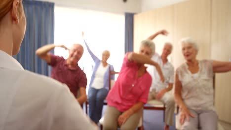 therapist assisting group of senior people with exercise