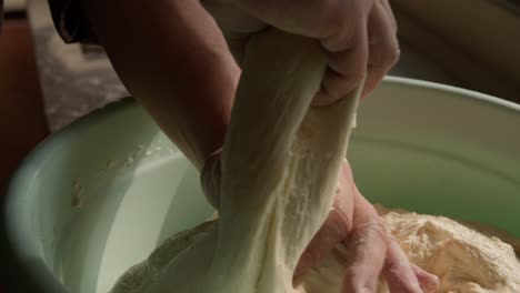 Kneading-yeast-dough-with-hands-in-a-bowl,-pie-preparation-process