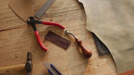 Close-up-of-tools-lying-on-table-in-leather-workshop