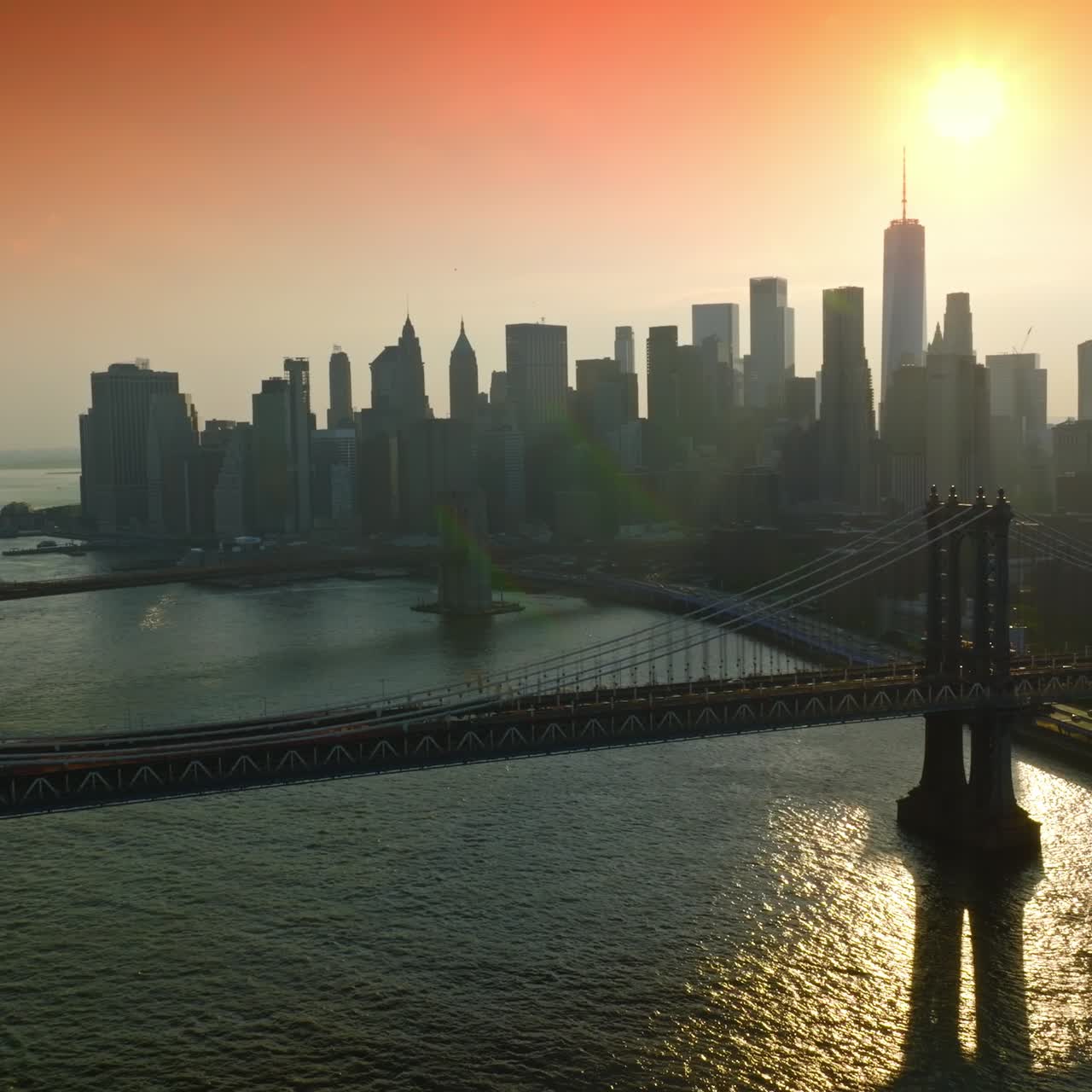 Grey silhouettes of gorgeous New York at sunset. Drone footage slowly approaching the stunning bridges over East River. Pink sky at backdrop