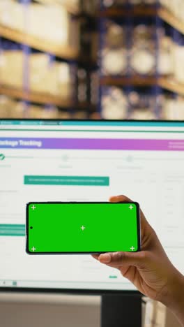 vertical video black woman holds phone with chroma key and monitors parcel shipment