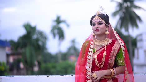 smiling indian bengali bride walks on roof under cloudy dark sky at sunset