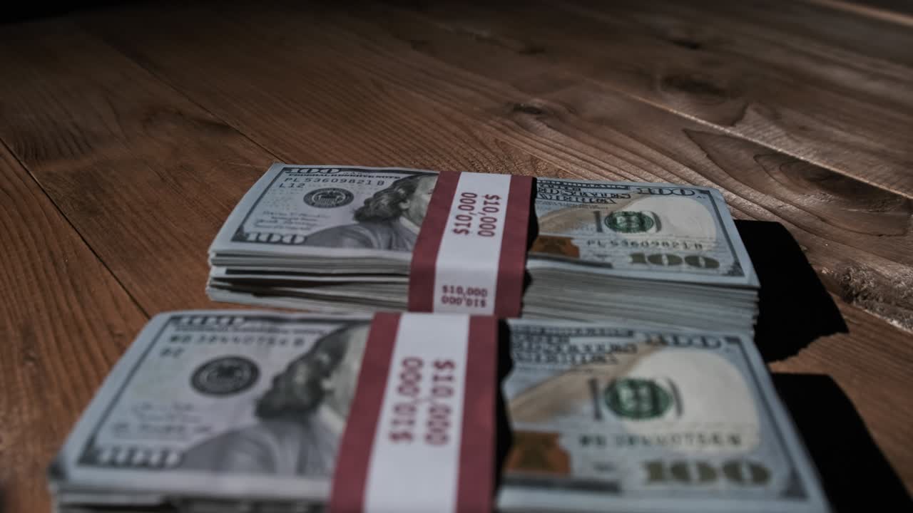 Three Stacks of 10000 American Dollars Banknotes in Bundles Lie on Wooden Table