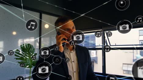network of digital icons against caucasian businessman talking on smartphone at office