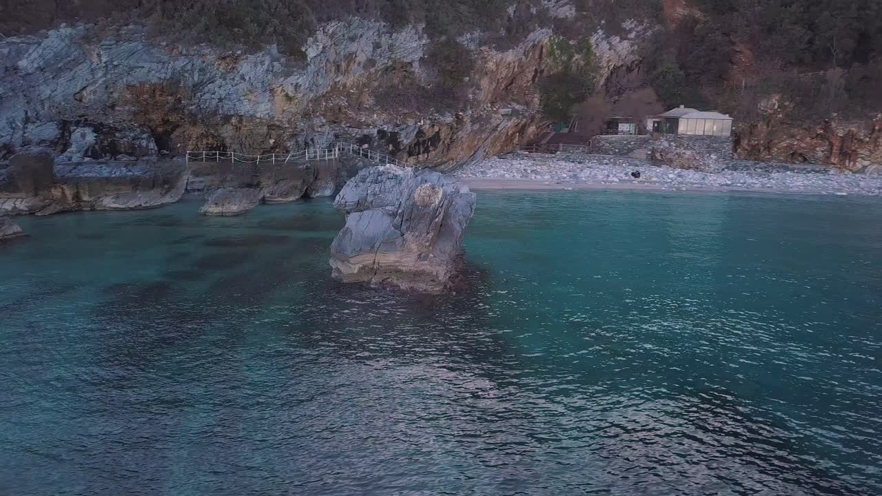 toma aérea de un dron en órbita más rápida de 4k de una gran roca en las aguas cristalinas del mar en grecia