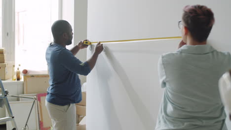 couple measuring wall for renovation