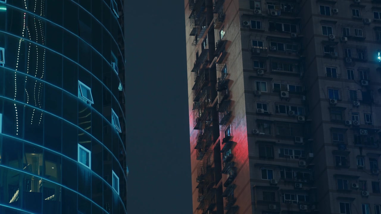 Grattacielo moderno in vetro a Chongqing che contrasta con un vecchio edificio residenziale con scale antincendio di notte, in stile Kooyanisqatsi.