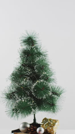 disparo vertical de un pequeño árbol de navidad en un soporte de madera sobre un fondo blanco