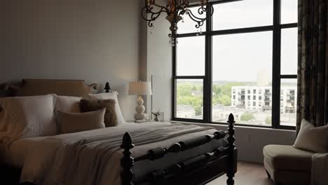 panning-reveal-shot-of-a-bedroom-with-white-accents-next-to-large-windows-letting-in-natural-light