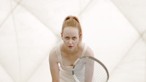 Half-portrait-of-focused-young-Caucasian-female-tennis-player-preparing-for-a-serve.-120-FPS-slow-motion,-4K-UHD-RAW-graded-footage