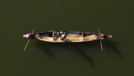 Aerial-shot-of-a-small-wooden-boat-with-fishermen-catching-fish-using-net-in-traditional-style-in-Surma-river,-Bangladesh