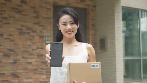 woman holding courier in hand showing pickup code on mobile phone delivery man uniform smiles during express, courier holding a small package parcel delivering goods to customer's home with van truck