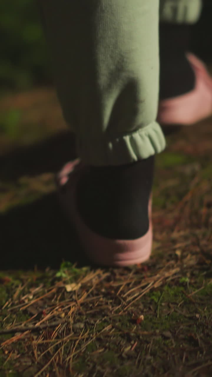 Female person in warm socks and comfortable pink slippers walks along illuminated path near house. Lady returning home after long day of activity in nature