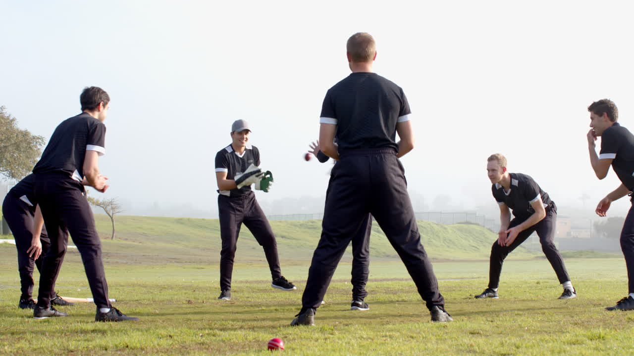 Playing cricket, team practicing on field, wearing black uniforms, enjoying game