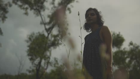clip de cerca de una flor rosa alta, luego mueve el enfoque a una hermosa modelo femenina vestida con un vestido azul de flores