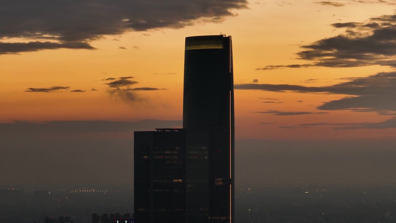 Toma de dron rodeando la silueta de un rascacielos, atardecer colorido en la Ciudad de México