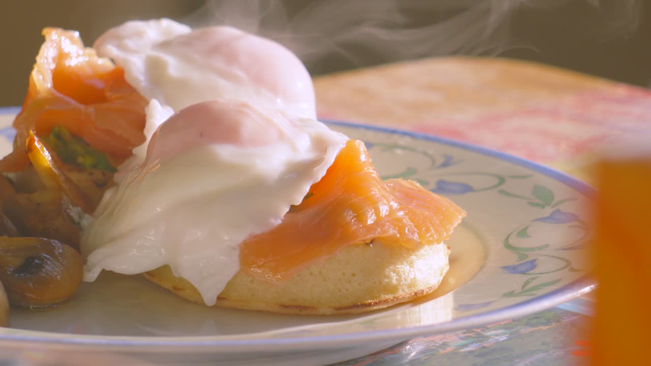 Breakfast Table Setting with Delicious Crumpet with Avocado Smoked Salmon Topped with Poached Egg with Steam Rising in Slow Motion. Morning High Protein Healthy Stylish Food Brunch Footage 4K.