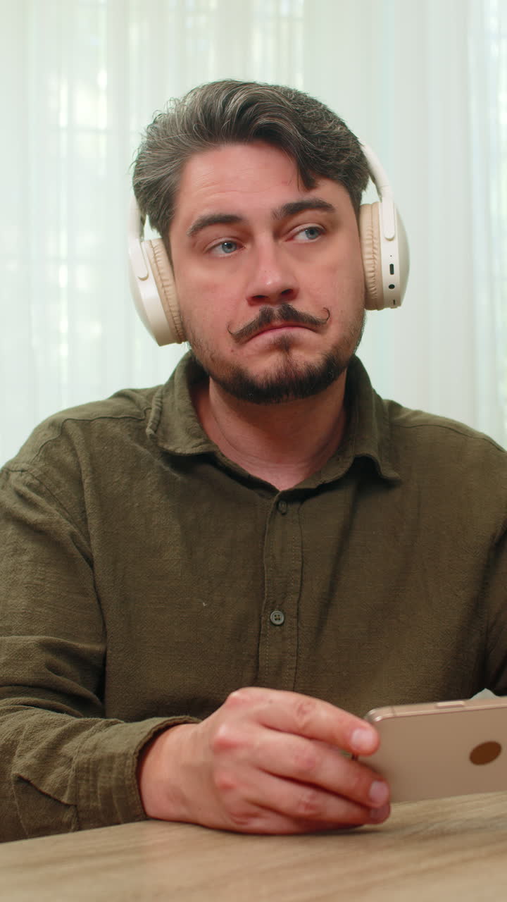 Middleaged man surprised hearing podcast smartphone headphones eyes widen amazed by news at table