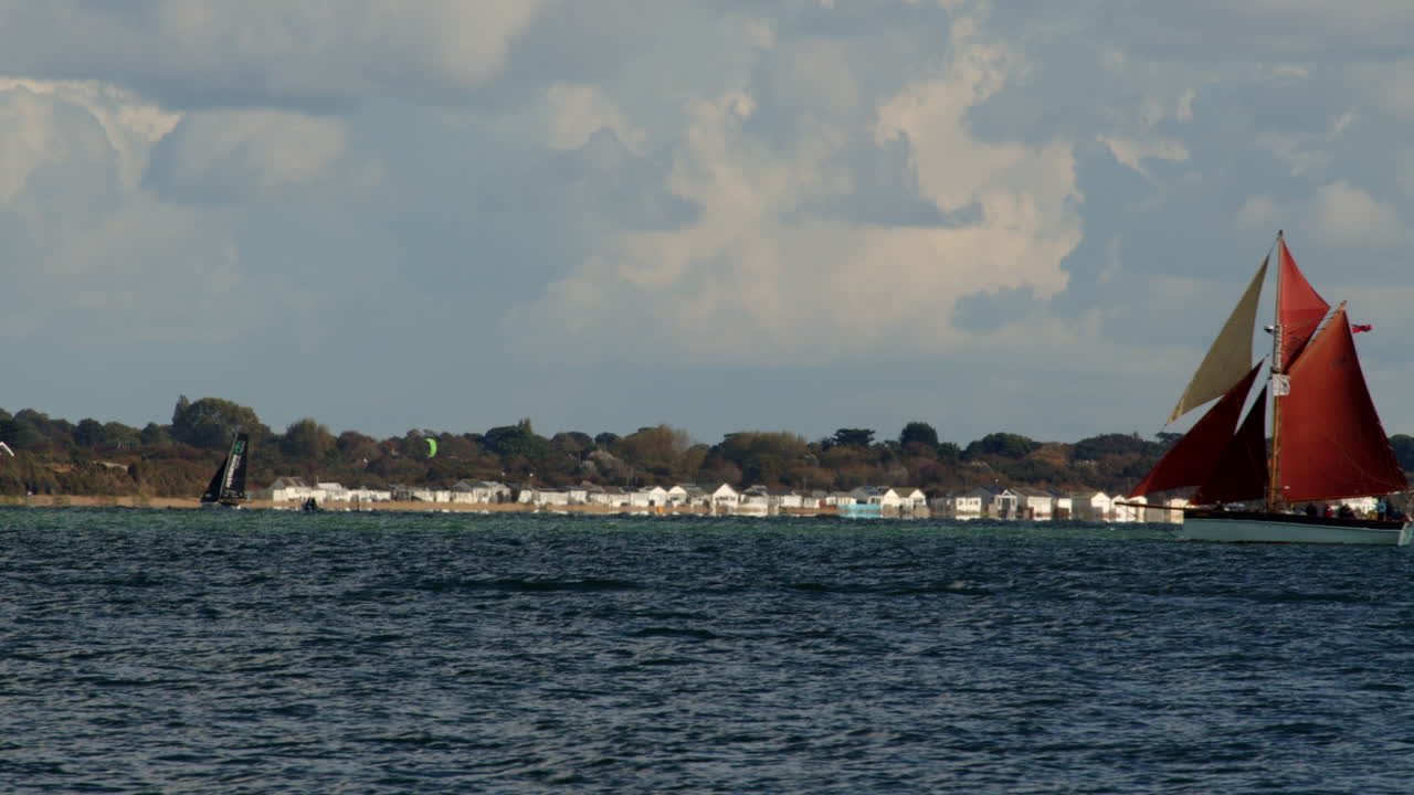 골든 바니티 (golden vanity) 라고 불리는 가프 커터 (gaff cutter) 가 웨스턴 (weston) 을 배경으로 프레임 안과 밖으로 항해합니다.