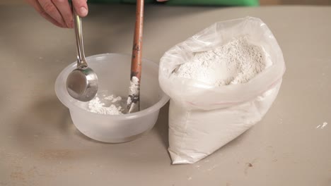 a close-up of potter preparing material clay for pottery. female sculptor is mixing clay and water for creating ceramics in her studio